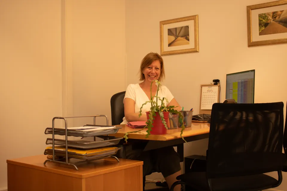 Membre de l'équipe d'Exactétudes souriante à son bureau, dans les locaux de Strasbourg