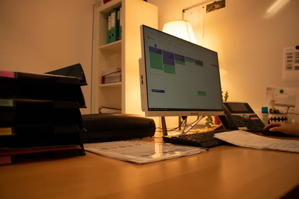 Poste de travail avec ordinateur et bannettes de documents dans un bureau d'Exactétudes