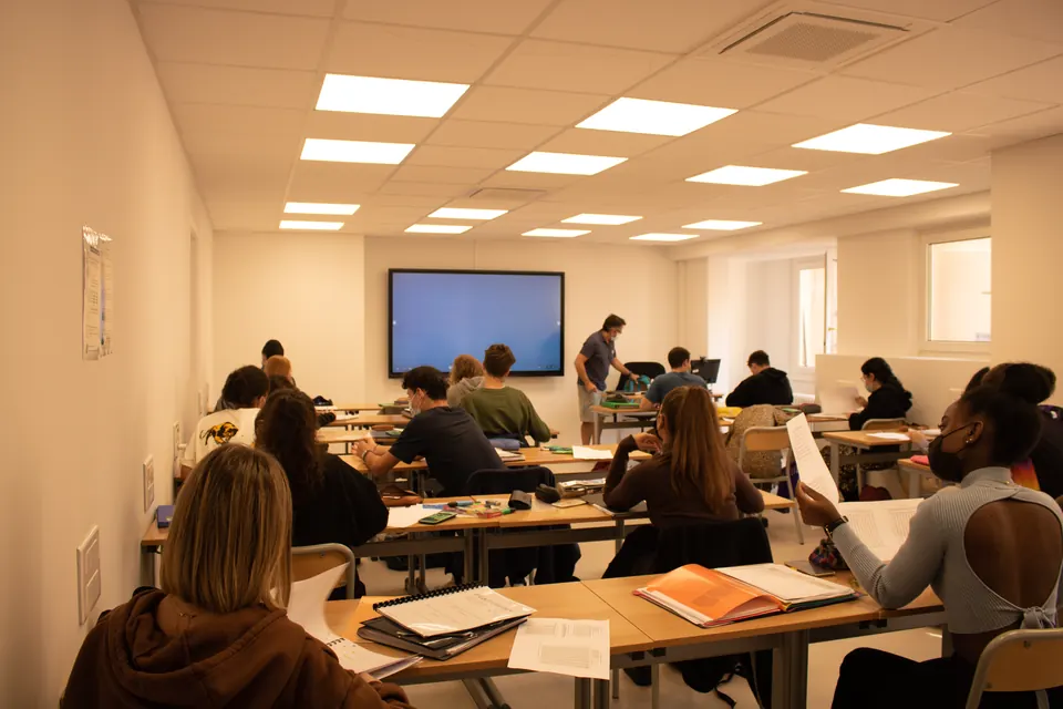 Groupe d'apprenants de dos, suivant un cours face à l'écran interactif