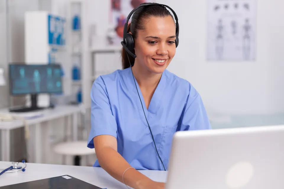 Secrétaire médicale, casque téléphonique sur la tête, travaillant sur ordinateur